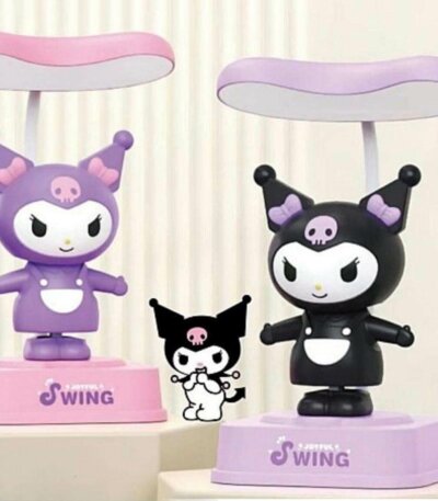 Deux lampes de bureau en forme de figurines Kuromi oscillantes sur des socles "Joyful Swing". À gauche, une version violette sur socle rose ; à droite, une version noire sur socle violet. Chaque figurine mesure 187 mm de hauteur et possède un abat-jour plat de couleur assortie au-dessus de sa tête.
