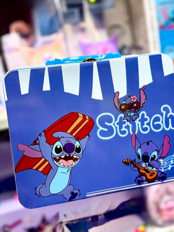 Valisette métallique de rangement bleu vif illustrée avec le personnage Disney Stitch dans trois poses : portant une planche de surf rouge, jouant de la guitare avec des notes de musique, et portant des lunettes de soleil roses avec une fleur. La boîte possède une poignée bleue et un fermoir en métal argenté.