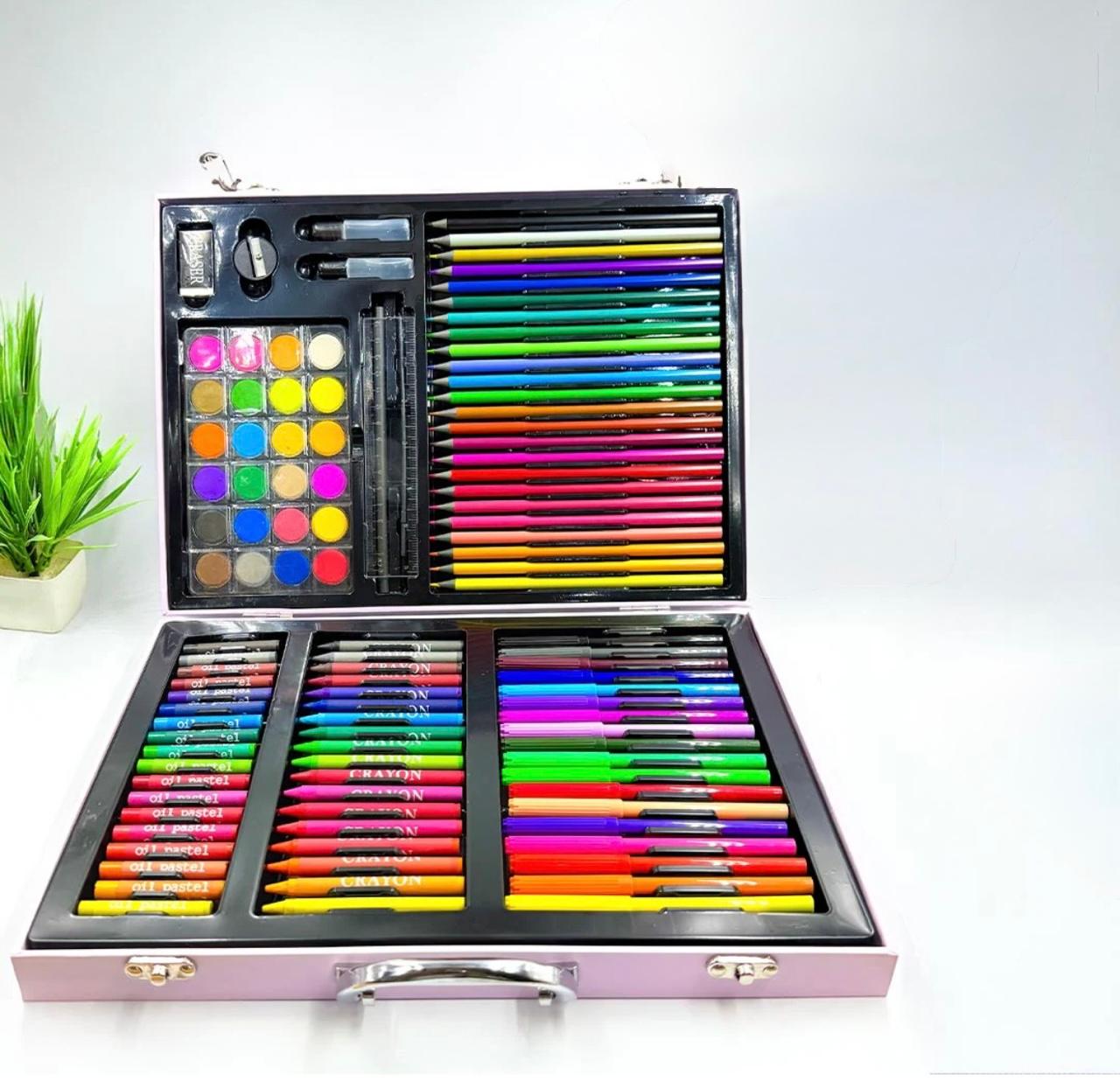 Une mallette d'artiste rose ouverte, posée à plat, révélant un contenu riche et coloré. La partie supérieure contient des crayons de couleur rangés par dégradés, une palette d'aquarelles circulaires, une règle et un taille-crayon