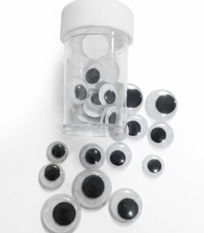 des yeux mobiles classiques (souvent appelés "googly eyes" en anglais), présentés dans un petit flacon transparent avec un bouchon blanc. Contrairement à l'assortiment multicolore vu précédemment, ceux-ci sont le modèle standard : une base blanche, une capsule transparente et une pupille noire mobile à l'intérieur.