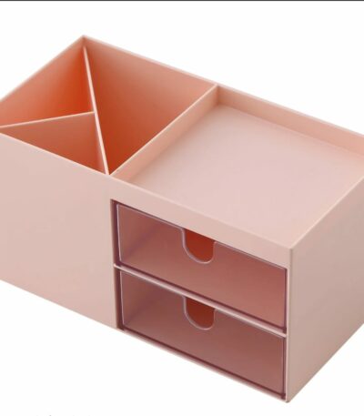 Organisateur de bureau en plastique rose pastel comprenant deux compartiments verticaux pour stylos, un plateau supérieur plat et deux tiroirs transparents superposés.