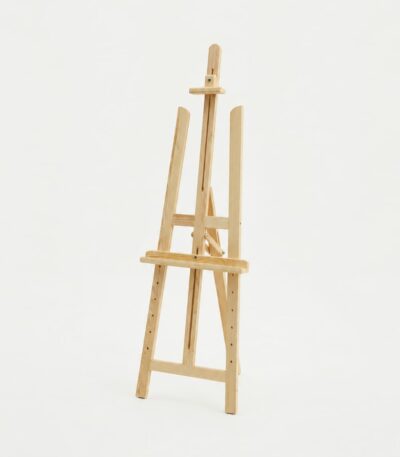 Un chevalet de peinture en bois clair de style trépied, vide, sur un fond blanc uni, montrant sa structure réglable.