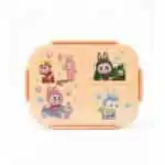 Une boîte à déjeuner (lunch box) pour enfant de couleur beige clair, encore sous emballage plastique transparent. Le couvercle est divisé visuellement en plusieurs zones décorées d'illustrations de style bande dessinée ou manga