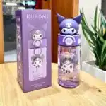 L'image montre une gourde réutilisable Kuromi (personnage de Sanrio) posée sur une table en bois clair, accompagnée de sa boîte d'emballage d'origine.Gourde Sanrio Kuromi avec Couvercle 3D et Paille.