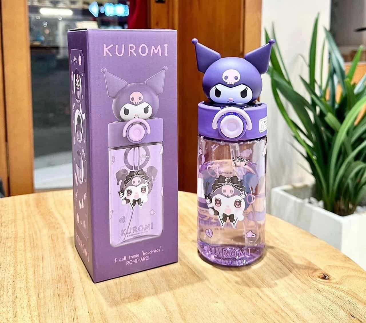 Gourde Sanrio Kuromi avec Couvercle 3D et Paille. L'image montre une gourde réutilisable Kuromi (personnage de Sanrio) posée sur une table en bois clair, accompagnée de sa boîte d'emballage d'origine.Gourde Sanrio Kuromi avec Couvercle 3D et Paille.