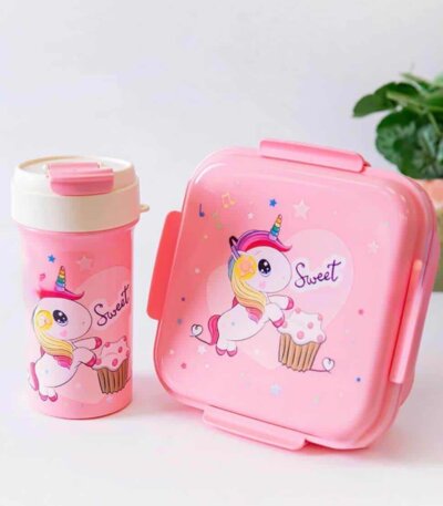 Une boîte à lunch carrée rose et une gourde assortie posées sur une surface blanche.