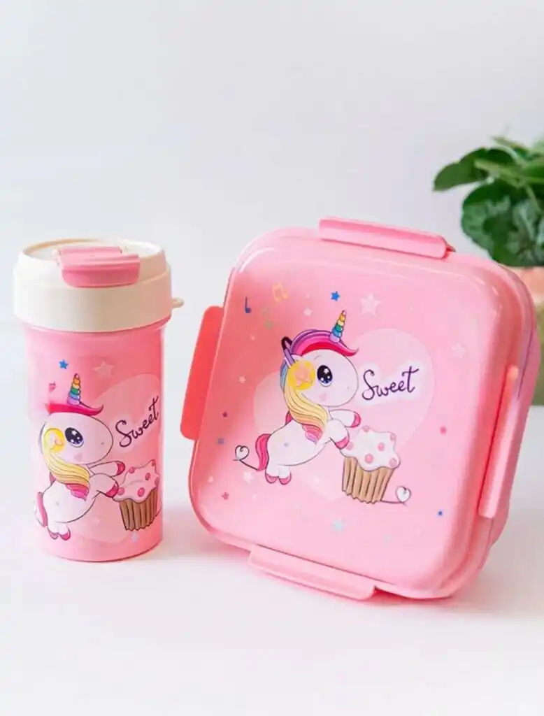 Une boîte à lunch carrée rose et une gourde assortie posées sur une surface blanche.