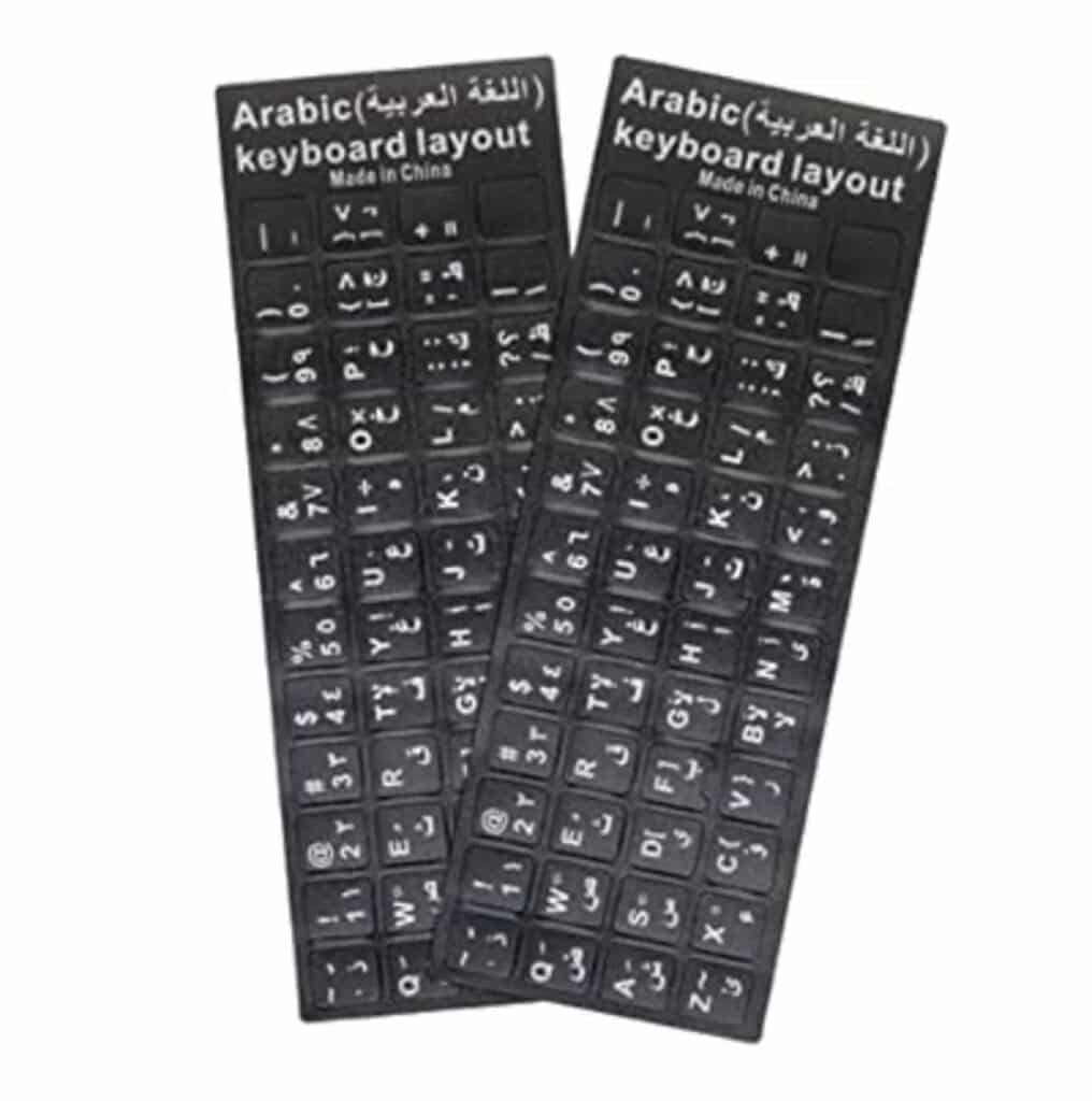 Deux planches rectangulaires d'autocollants noirs pour clavier d'ordinateur sont posées côte à côte sur un fond blanc uni. Chaque planche comporte un en-tête noir avec l'inscription « Arabic (اللغة العربية) keyboard layout » et la mention « Made in China » écrites en blanc. Les autocollants individuels correspondent aux touches d'un clavier standard et affichent des caractères blancs, combinant des lettres de l'alphabet latin (disposition QWERTY), des chiffres et des caractères de l'alphabet arabe.