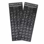 Deux planches rectangulaires d'autocollants noirs pour clavier d'ordinateur sont posées côte à côte sur un fond blanc uni. Chaque planche comporte un en-tête noir avec l'inscription « Arabic (اللغة العربية) keyboard layout » et la mention « Made in China » écrites en blanc. Les autocollants individuels correspondent aux touches d'un clavier standard et affichent des caractères blancs, combinant des lettres de l'alphabet latin (disposition QWERTY), des chiffres et des caractères de l'alphabet arabe.