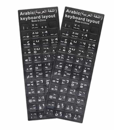 Deux planches rectangulaires d'autocollants noirs pour clavier d'ordinateur sont posées côte à côte sur un fond blanc uni. Chaque planche comporte un en-tête noir avec l'inscription « Arabic (اللغة العربية) keyboard layout » et la mention « Made in China » écrites en blanc. Les autocollants individuels correspondent aux touches d'un clavier standard et affichent des caractères blancs, combinant des lettres de l'alphabet latin (disposition QWERTY), des chiffres et des caractères de l'alphabet arabe.