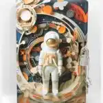 Une figurine ou illustration centrale en relief représentant un astronaute en combinaison spatiale blanche et détails orange, debout sur une structure circulaire.