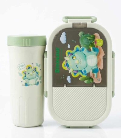 Ensemble de repas pour enfant comprenant une boîte à déjeuner ovale et une gourde assortie de couleur blanc cassé et vert menthe. Le couvercle de la boîte et le devant de la gourde sont décorés d'un petit tricératops bleu rigolo entouré de cactus