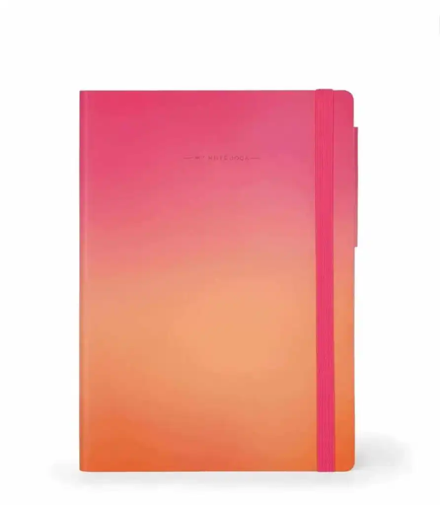 Carnet de notes rigide avec un dégradé de couleurs allant du rose fuchsia sur le dessus à l'orange vif sur le bas. La couverture affiche la mention "MY NOTEBOOK" centrée et dispose d'un élastique de fermeture vertical plat de couleur rose vif sur le côté droit.