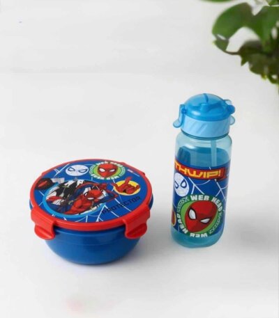 « Un ensemble de repas pour enfant sur le thème de Spider-Man, posé sur une surface blanche. Il comprend une boîte à déjeuner ronde de couleur bleue avec un couvercle rouge illustré par Spider-Man et Ghost-Spider, ainsi qu'une gourde bleue transparente assortie ornée du visage de Spider-Man