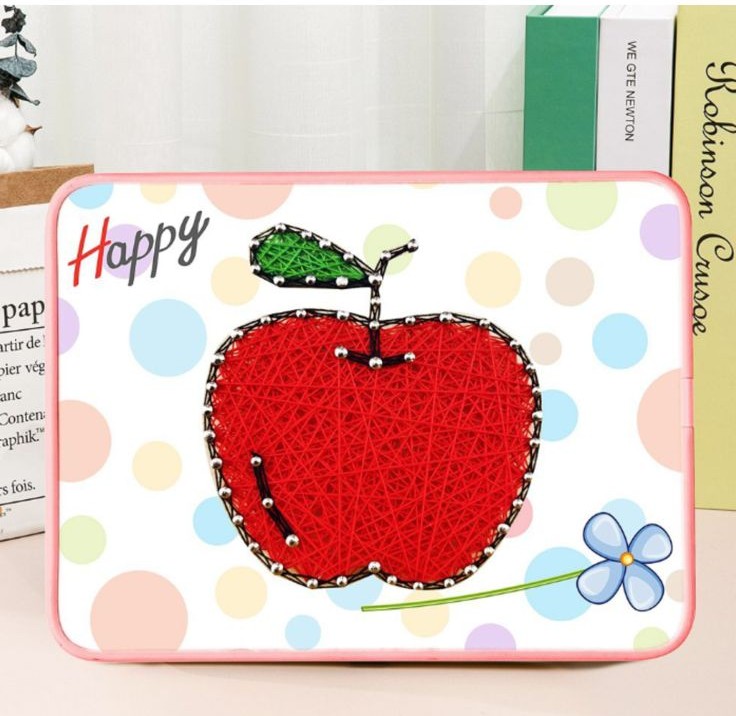Kit de String Art Pomme Happy – Tableau en Fils Tendus pour Débutants Un tableau en art filaire représentant une grosse pomme rouge sur un support blanc à motifs de gros confettis pastel (bleus, roses, jaunes). La pomme est tissée de fils rouges denses, surmontée d'une petite tige noire et d'une feuille en fils verts. Les contours du fruit sont dessinés par des clous argentés. Le cadre rectangulaire possède des bords arrondis de couleur rose.