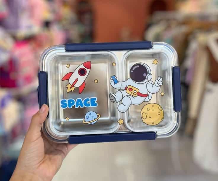 Une boîte à lunch rectangulaire à deux compartiments avec un couvercle transparent orné de motifs spatiaux
