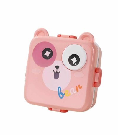 Une boîte à repas (lunch box) pour enfant de couleur rose pâle, en forme de tête d'ours stylisée. Le couvercle présente deux oreilles arrondies sur le dessus et un visage d'ours avec un œil rose, un œil blanc et un petit nez noir.