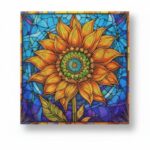 Un tableau carré de broderie diamant représentant un grand tournesol jaune et orange stylisé comme un vitrail. Le cœur de la fleur forme un mandala aux cercles concentriques verts et bleus, tandis que les pétales sont recouverts de points texturés et de strass. L'arrière-plan imite une mosaïque de verre plombé dans des teintes bleu ciel, turquoise et violettes. Le tableau projette une ombre douce sur un fond blanc uni.