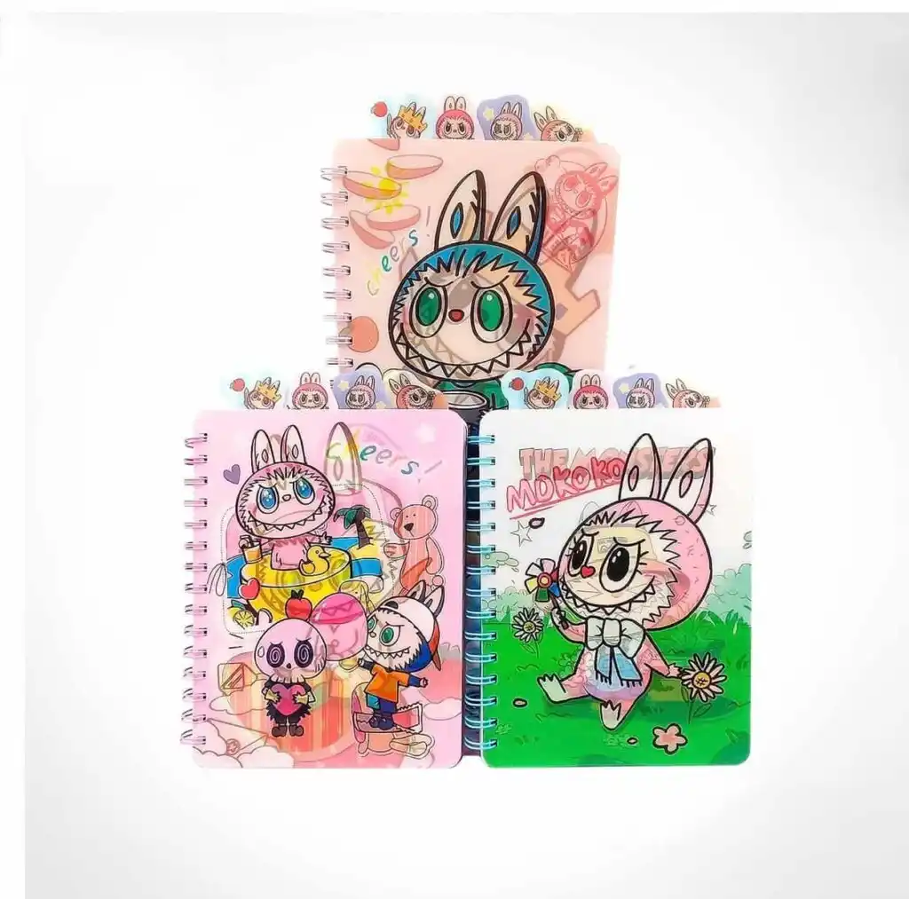 Trois cahiers de notes à spirales de la collection Labubu et The Monsters disposés en pyramide sur un fond blanc uni. Chaque carnet transparent en plastique affiche des illustrations colorées de Labubu et Mokoko, et intègre des intercalaires avec des onglets illustrés en haut de la couverture.