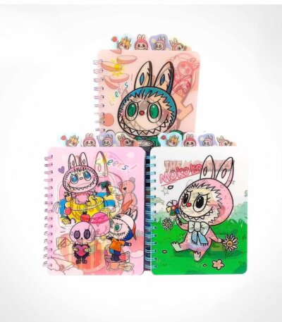 Trois cahiers de notes à spirales de la collection Labubu et The Monsters disposés en pyramide sur un fond blanc uni. Chaque carnet transparent en plastique affiche des illustrations colorées de Labubu et Mokoko, et intègre des intercalaires avec des onglets illustrés en haut de la couverture.