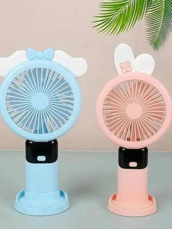 Deux mini ventilateurs portables rechargeables au design mignon, posés côte à côte sur une surface plane vert clair. À gauche, un modèle bleu clair est décoré sur le dessus d'un nœud papillon bleu posé sur de petites ailes blanches.