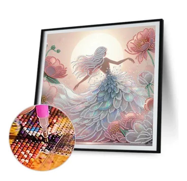 bKit Broderie Diamant 5D - Femme en Robe Scintillante sous la Lune Un kit de broderie diamant montrant un tableau encadré représentant une femme de dos avec de longs cheveux clairs, vêtue d'une robe volumineuse faite de strass scintillants, entourée de grandes fleurs roses sous une pleine lune lumineuse. En bas à gauche, un gros plan circulaire met en évidence l'utilisation d'un stylet rose qui dépose précisément un petit strass brillant sur la toile quadrillée et numérotée.