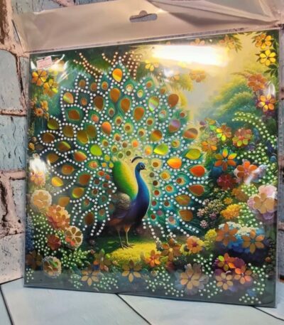 Kit de broderie diamant emballé représentant un paon majestueux qui fait la roue au milieu d'un jardin fleuri étincelant avec des strass brillants.