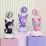 Trois ventilateurs de bureau en forme de figurine Kuromi déclinés en noir, violet et rose sur des présentoirs.