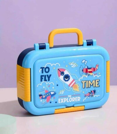 L'image montre une boîte à lunch isotherme pour enfants, de forme rectangulaire avec des coins arrondis, principalement de couleur bleu ciel. Elle possède une poignée de transport et des clips de fermeture jaunes, ainsi qu'un corps bleu marine sur les côtés.