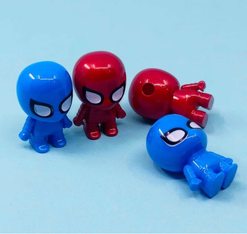 Quatre petits taille-crayons en plastique en forme de figurines de Spider-Man, déclinés en rouge brillant et en bleu vif. Deux figurines sont debout de face, tandis que les deux autres sont allongées, révélant le trou d'insertion pour le crayon situé au sommet de la tête de l'une d'elles.