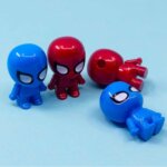 Quatre petits taille-crayons en plastique en forme de figurines de Spider-Man, déclinés en rouge brillant et en bleu vif. Deux figurines sont debout de face, tandis que les deux autres sont allongées, révélant le trou d'insertion pour le crayon situé au sommet de la tête de l'une d'elles.