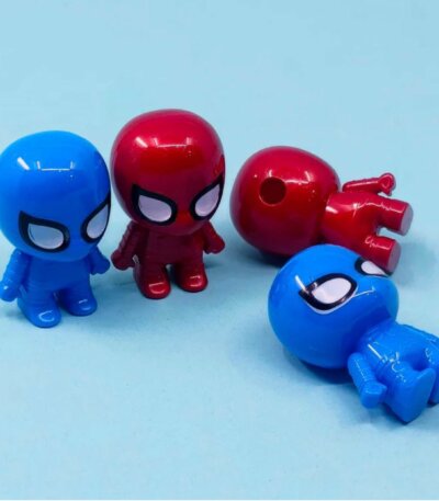 Quatre petits taille-crayons en plastique en forme de figurines de Spider-Man, déclinés en rouge brillant et en bleu vif. Deux figurines sont debout de face, tandis que les deux autres sont allongées, révélant le trou d'insertion pour le crayon situé au sommet de la tête de l'une d'elles.
