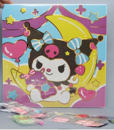 Un kit de broderie diamant représentant le personnage Kuromi de Sanrio. La toile carrée montre Kuromi avec sa coiffe noire à tête de mort rose, assise sur un croissant de lune jaune vif et tenant une petite peluche violette. L'arrière-plan est décoré d'étoiles, de cœurs roses et de vagues de couleurs pastel violettes et bleues. Toute la surface est recouverte de petits cercles numérotés prêts à recevoir les strass. Au premier plan, au pied de la toile posée à la verticale, se trouvent plusieurs sachets plastiques transparents alignés contenant les diamants colorés (rose, blanc, vert, violet).