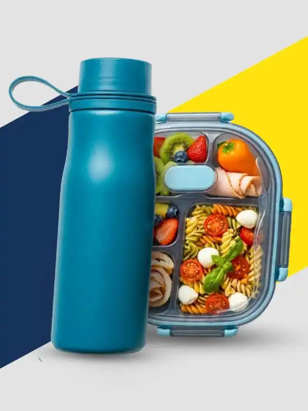 Vue de dessus d'une gourde réutilisable bleu canard à côté d'une lunch box compartimentée contenant une salade de pâtes, des tranches de kiwi, des fraises, des myrtilles et des roulés de dinde sur un fond blanc épuré.